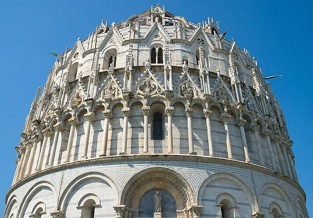 Detail of the Baptistery of Pisa from below: tiers of arches and Gothic pinnacles rising above the main portal