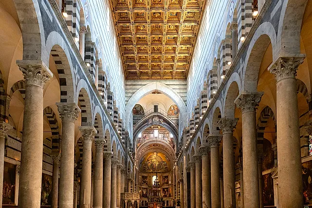 Inside Pisa Cathedral: the nave with its tall columns, the gilded coffered ceiling and the apse at the far end