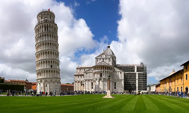 The Leaning Tower and the Cathedral side by side on the green lawn of Piazza dei Miracoli under a cloudy sky
