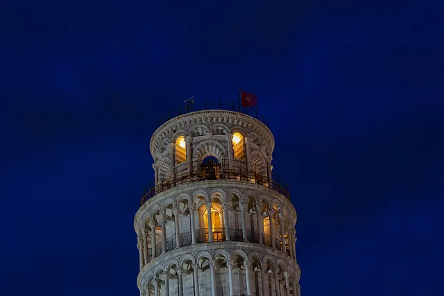 The Leaning Tower of Pisa lit up at night against a deep blue sky